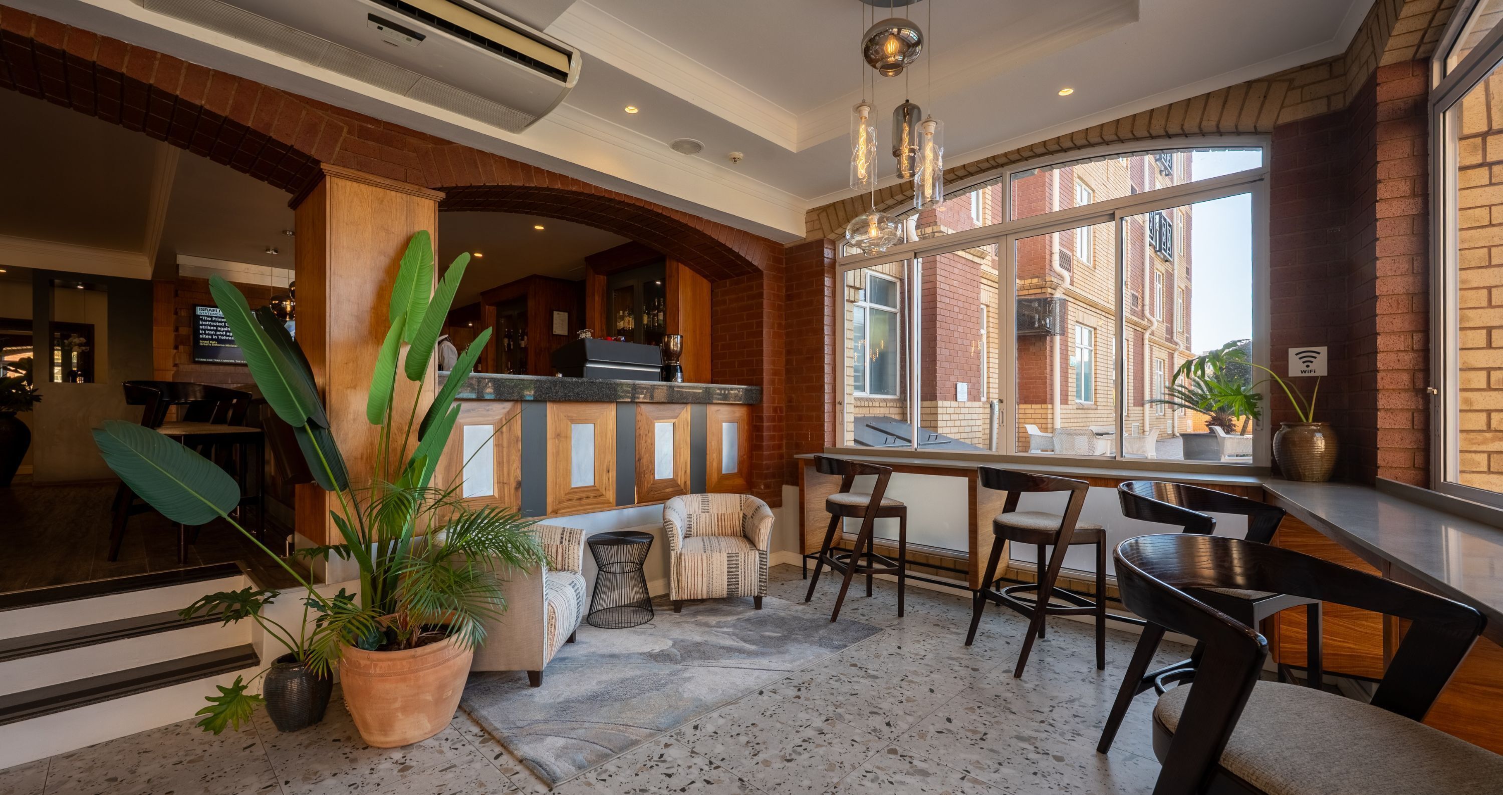A bar area with seating, a counter, and large windows offering a view of the street.