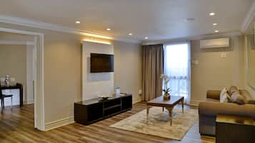Un salon moderne avec un téléviseur à écran plat fixé au mur, un meuble de rangement en bois foncé, un canapé beige et une table basse.