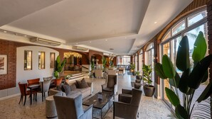 Un hall espacioso con diversas zonas de estar, un piano y amplias ventanas con vistas.
