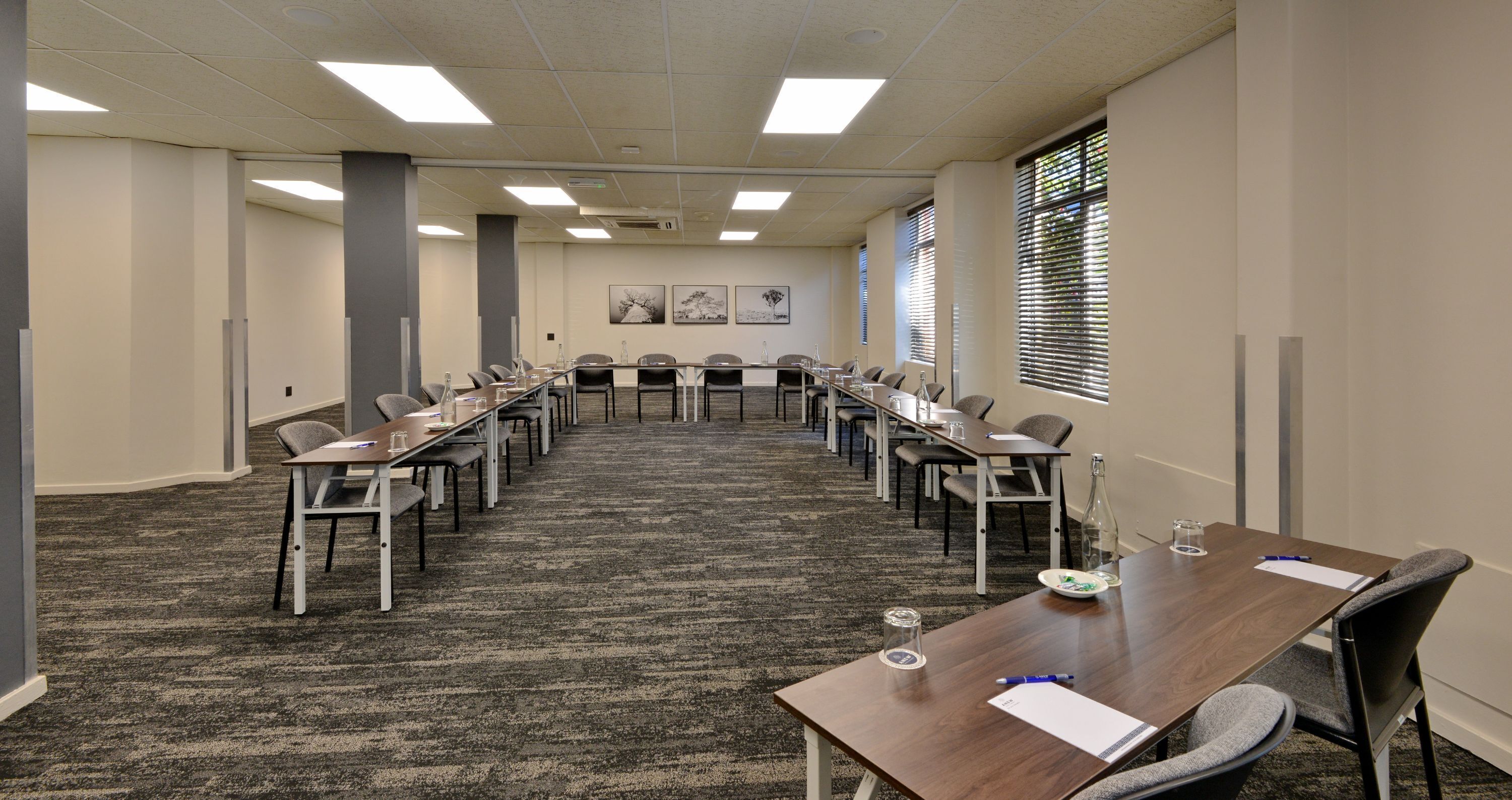 A conference room with a long table, chairs, and a carpeted floor.