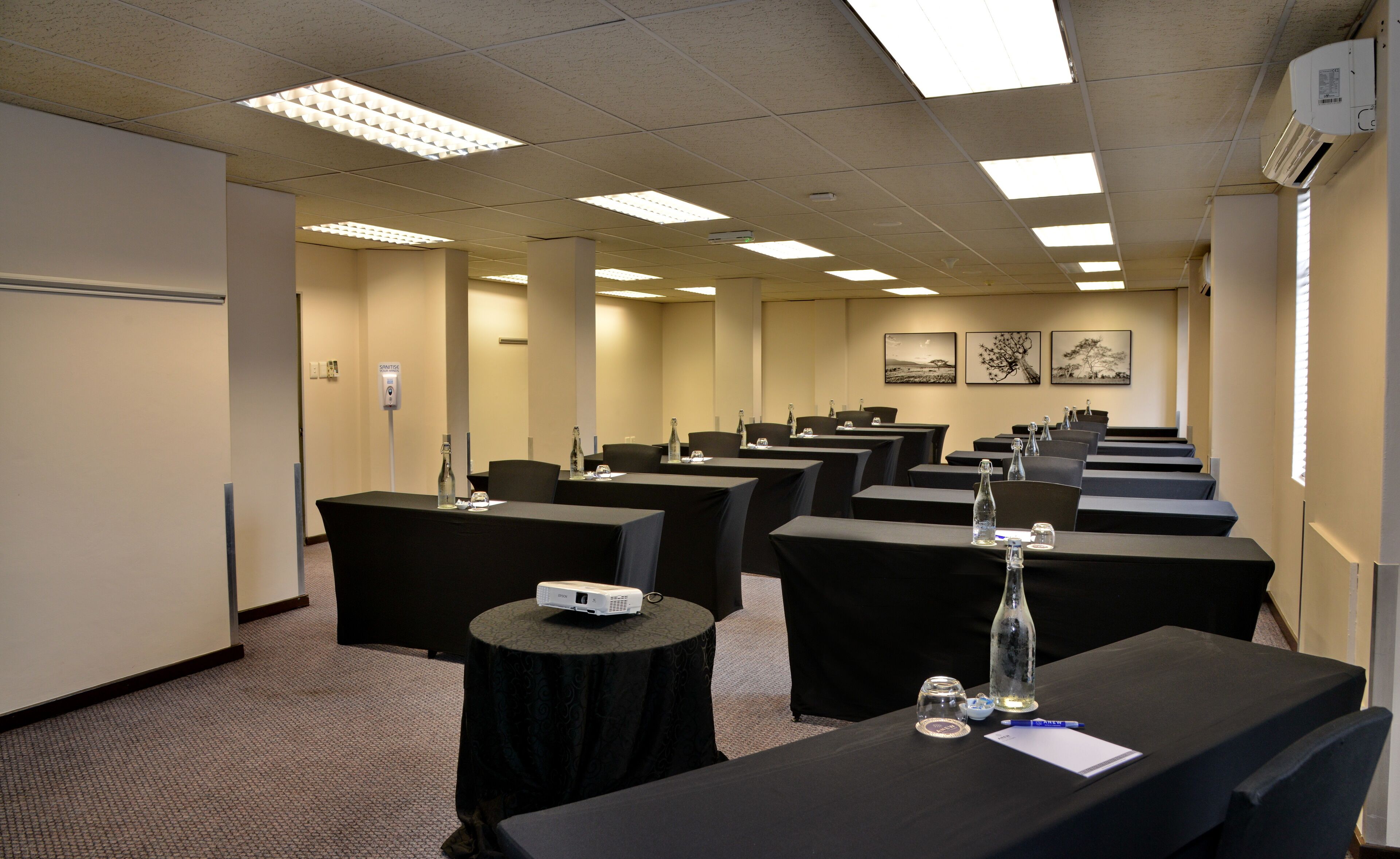 Une salle de conférence avec des rangées de tables, des chaises et un projecteur posé sur une table.