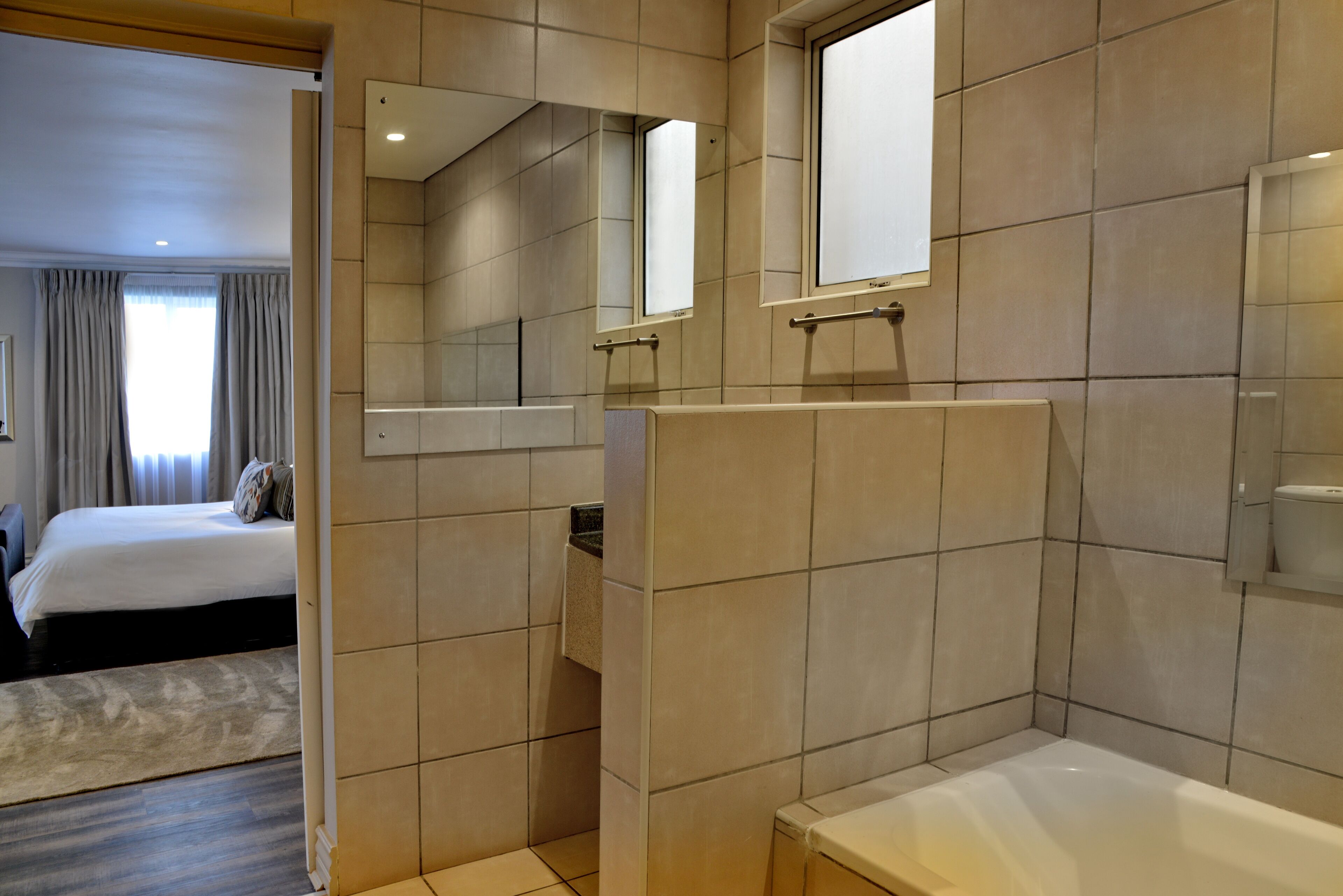 A modern bathroom with a bathtub, a shower area, and a mirror.