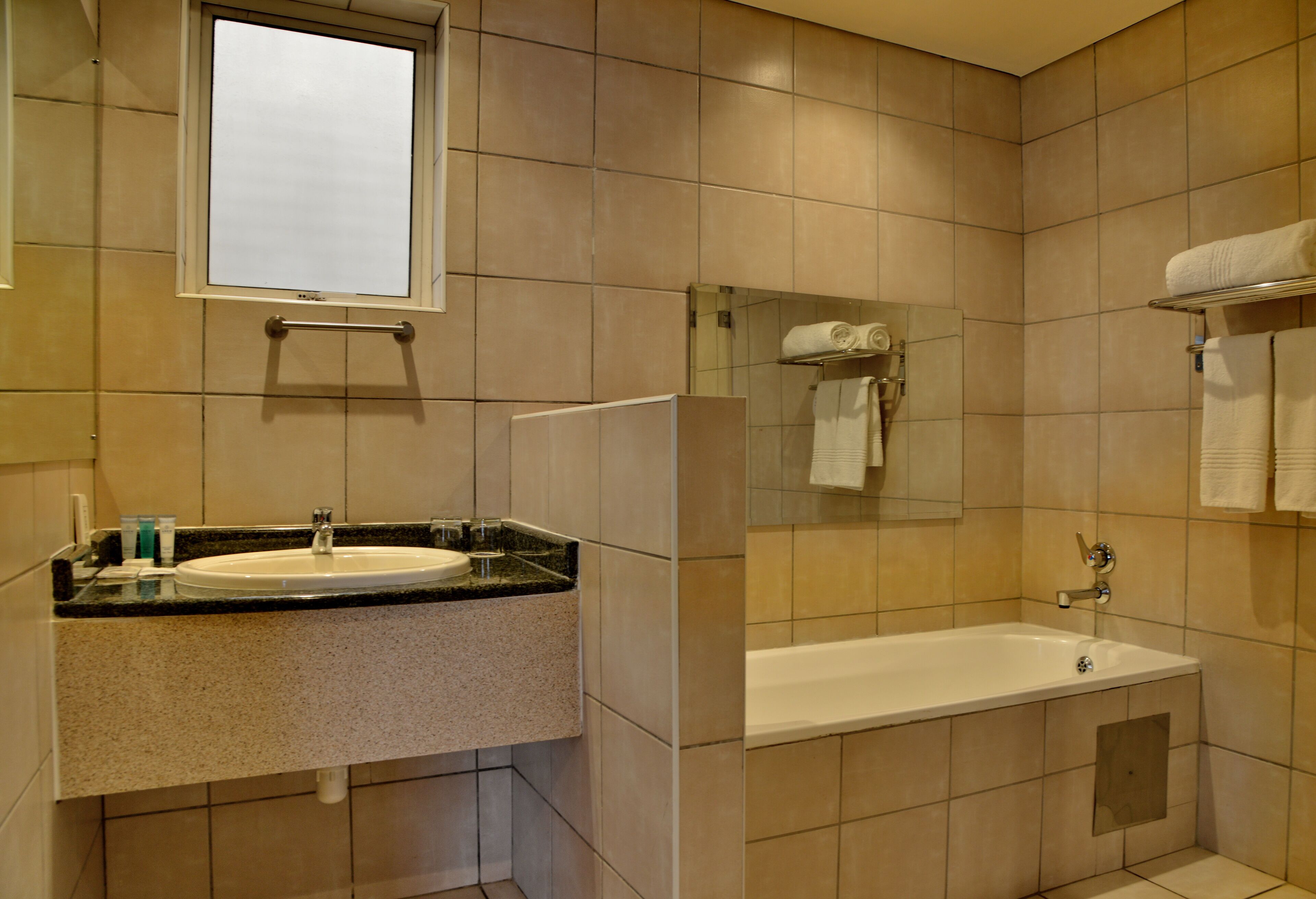 A bathroom with a sink, mirror, and bathtub.