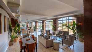 Un espacio interior amplio con una gran mesa y diversas opciones de asiento, incluyendo sofás y sillones, dispuestos alrededor de una mesa de centro.