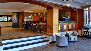 Un interior moderno con una zona de bar, asientos y una escalera que lleva a otro nivel.