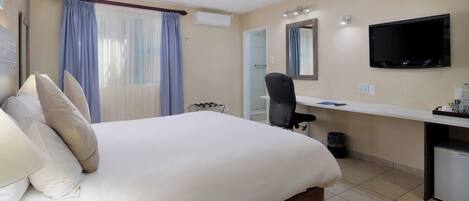 Een hotelkamer met een bed, een bureau, een stoel, een televisie en een spiegel.