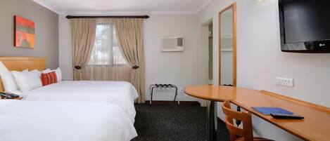 A hotel room with two beds, a desk, a chair, a TV, and a window with curtains.