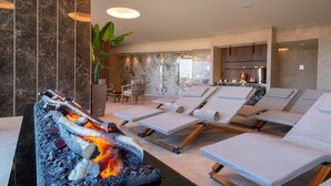 A spa area with a fire feature, reclining chairs, and a seating area with a plant. - Relais & Spa Castello di Casiglio (Erba)