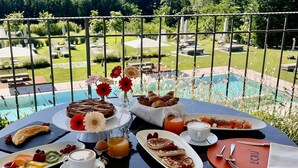 A table set for breakfast with a view of a pool and greenery. - Relais & Spa Castello di Casiglio (Erba)
