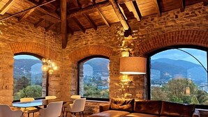 A cozy interior with stone walls, a wooden ceiling, and large windows offering a view of the mountains. - Relais & Spa Castello di Casiglio (Erba)