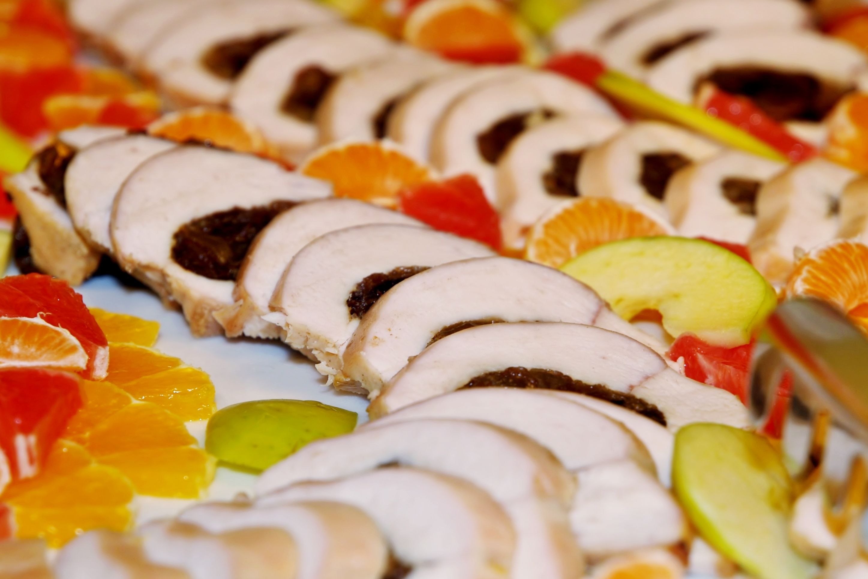 A sliced meat dish with fruit garnish.