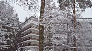 A multi-story building with a snow-covered exterior, surrounded by trees and a bench in a snowy outdoor area. - Hotel Lövér Sopron (Sopron)