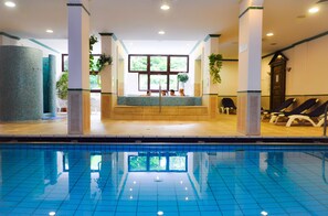 Una piscina cubierta, tumbonas