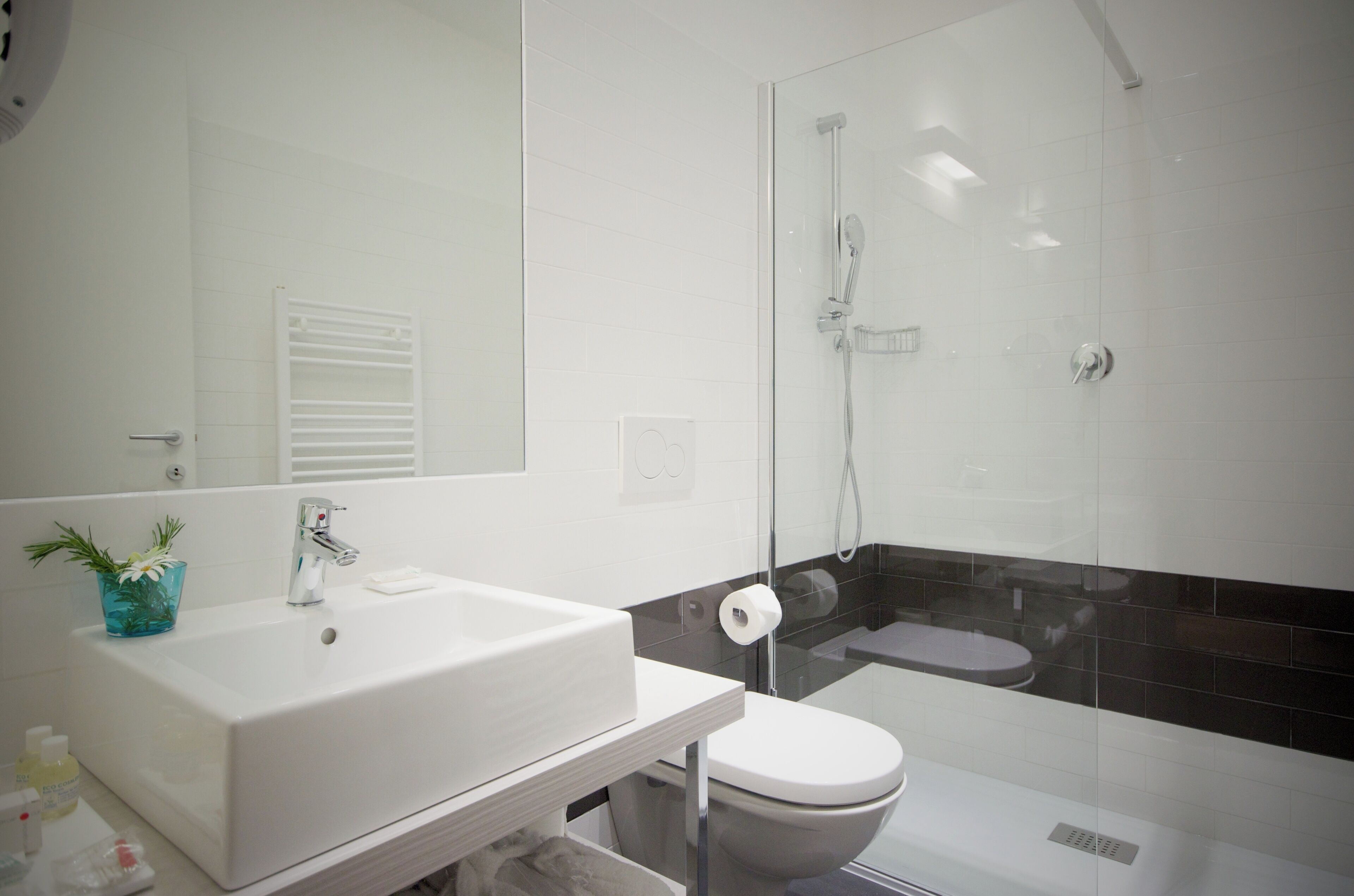 Un baño moderno con lavamanos blanco, inodoro y ducha con mampara de vidrio.