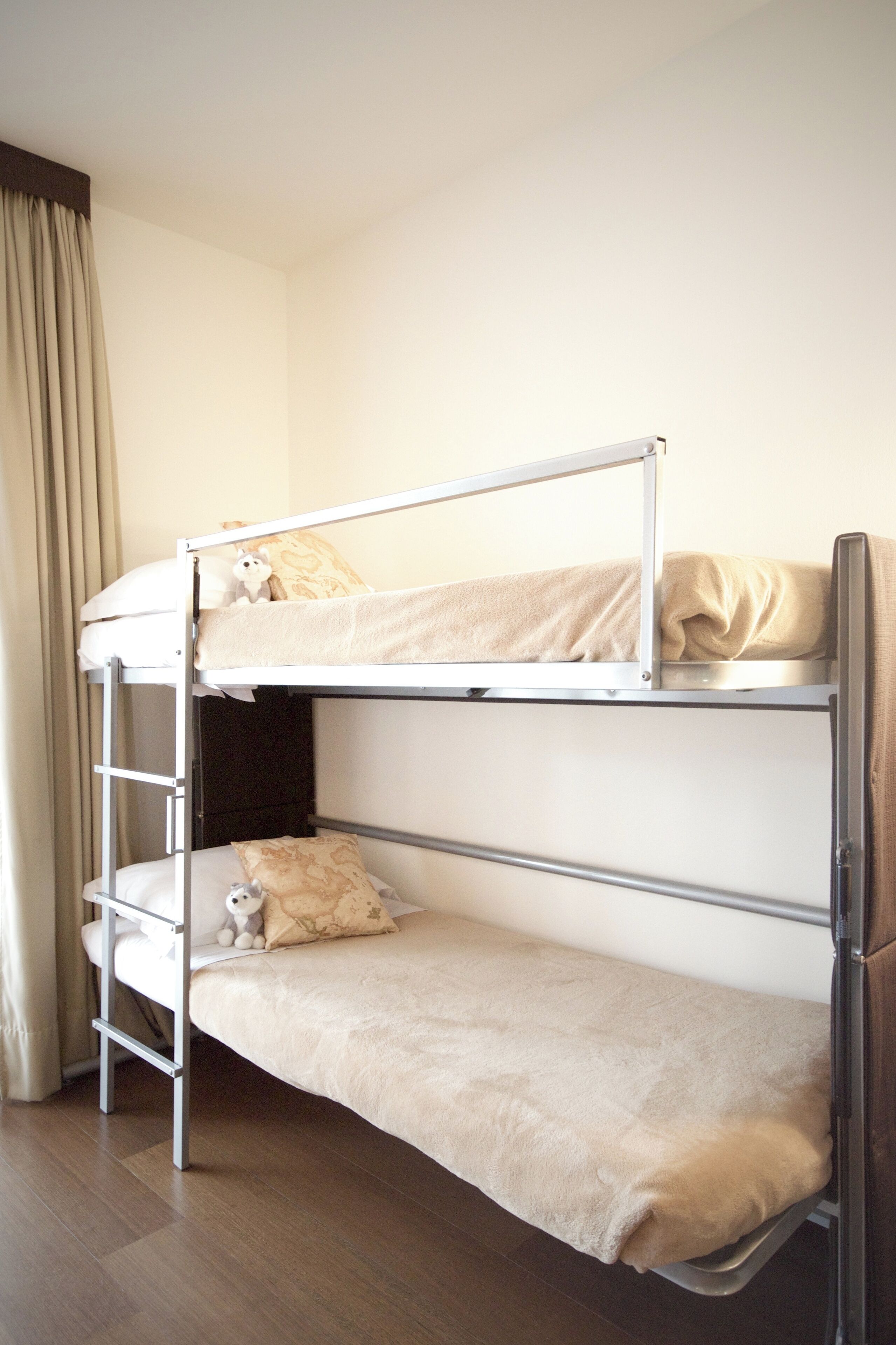 Una cama litera con una cama inferior y una superior, ambas con ropa de cama color beige.