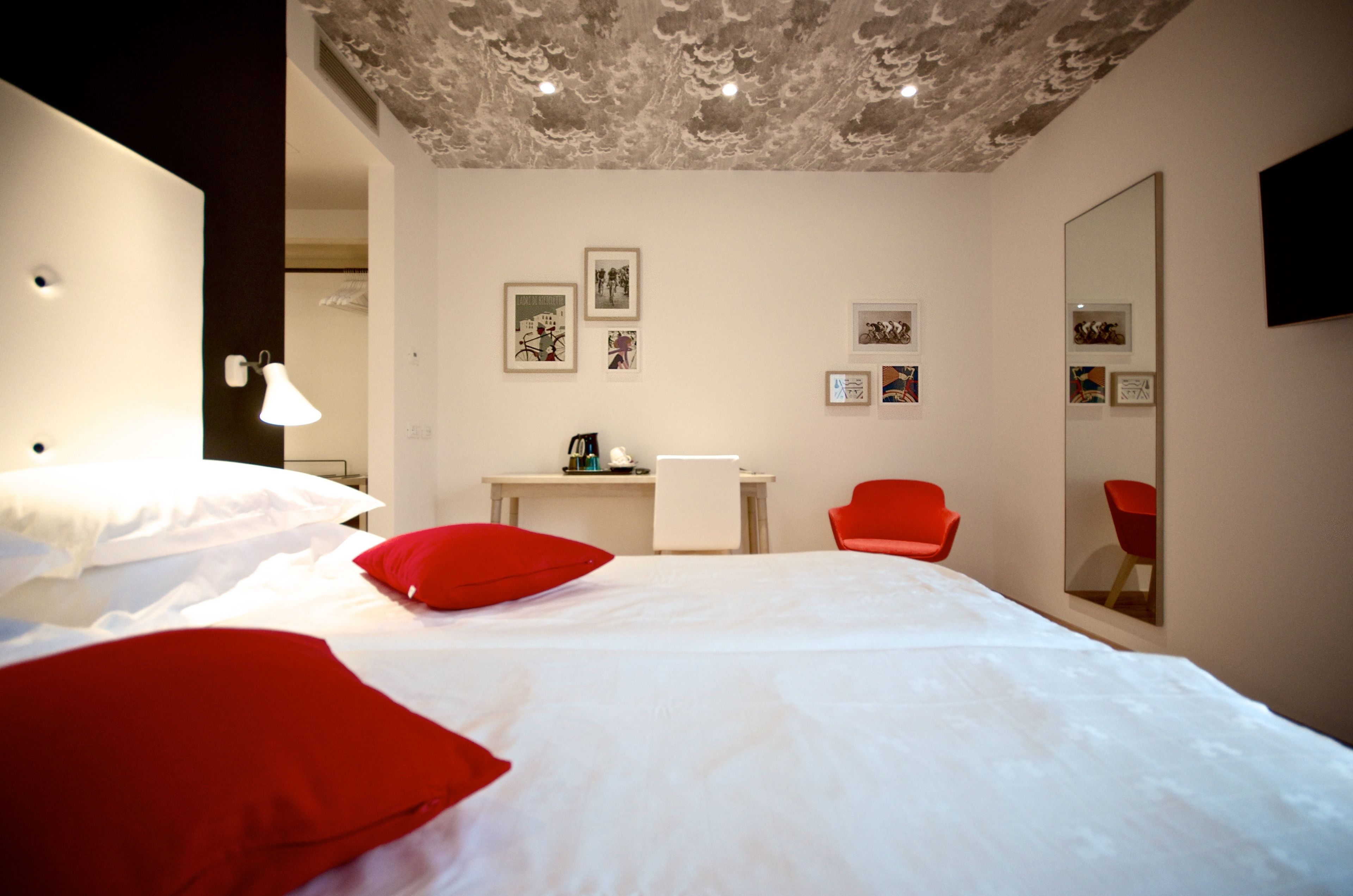 A hotel room with a bed, a desk, a chair, and a large mirror.