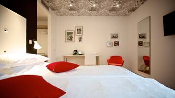 Een hotelkamer met een bed, een bureau, een stoel en een grote spiegel.