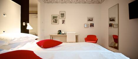 A hotel room with a bed, a desk, a chair, and a large mirror.