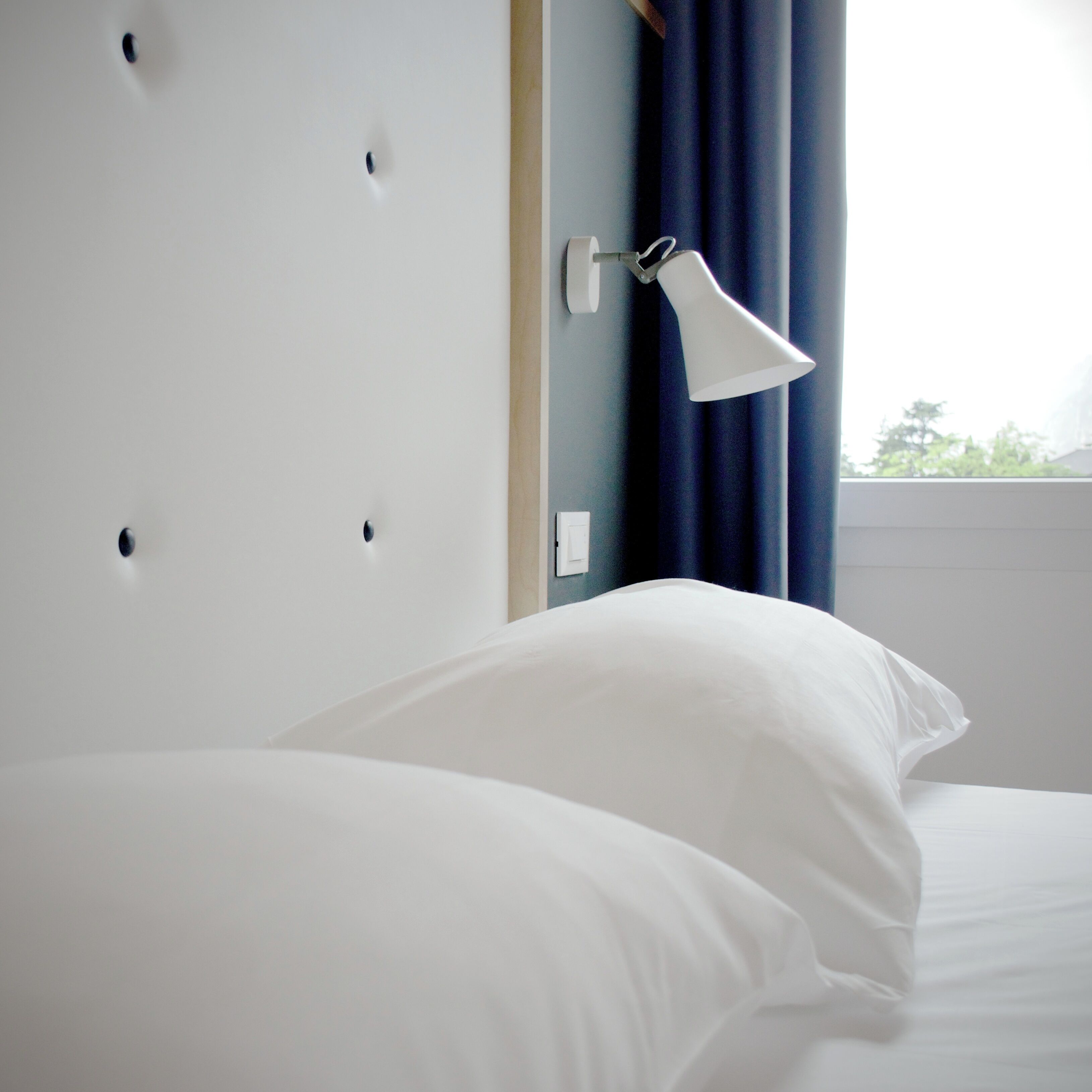 A neatly made bed with white linens in a hotel room.