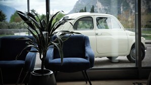 Una stanza con una grande finestra, una pianta in vaso e un'auto bianca parcheggiata all'esterno.