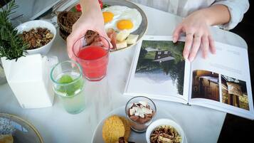 A breakfast setting with various food items and a book on a table.