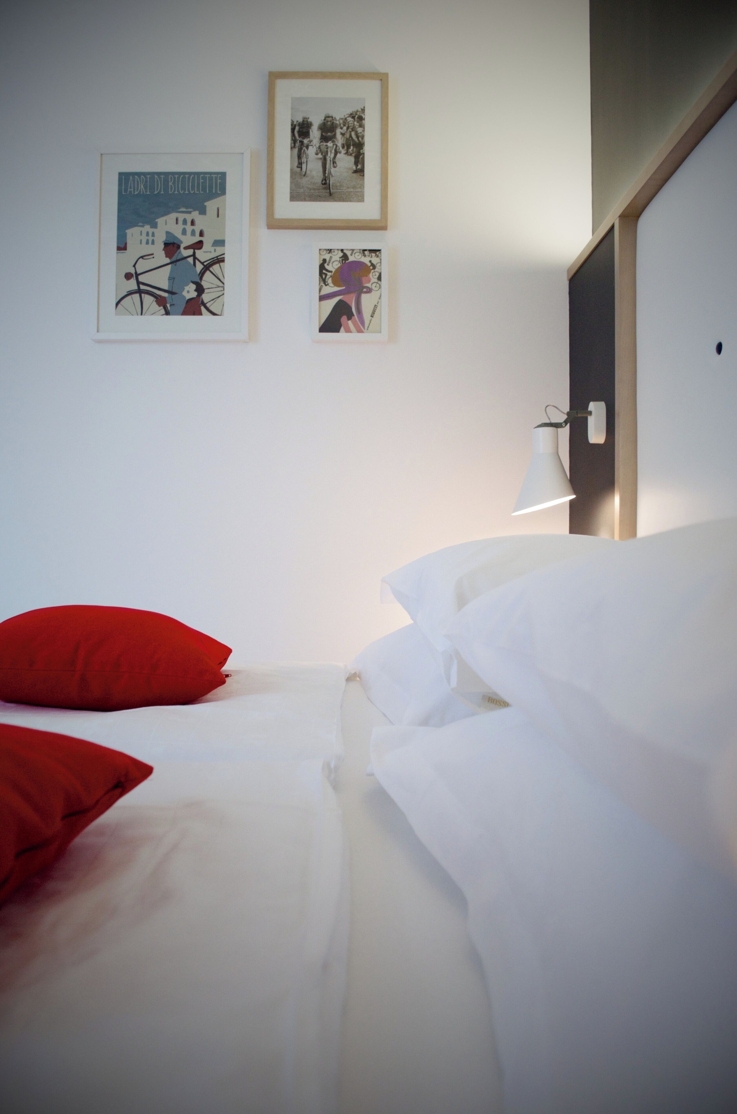 Una camera d'albergo con un letto, cuscini rossi e tre quadri appesi al muro.