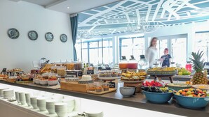 Un buffet con diversi cibi e bevande, un banco con piatti, e una persona sullo sfondo.