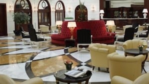 Un vestíbulo amplio con suelo de cuadros, un sofá rojo y varios sillones.