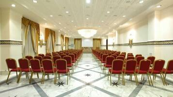 A conference room with rows of red chairs, a marble floor with star patterns, and a ceiling with recessed lighting.