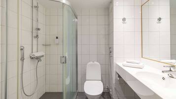A modern bathroom with a glass-enclosed shower, a white toilet, and a vanity with a mirror.