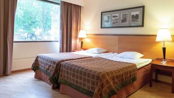 A hotel room with two beds, a window with curtains, a framed picture on the wall, and two bedside lamps.