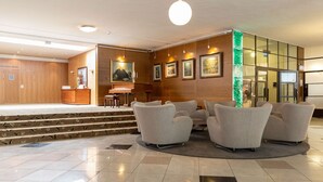A lobby with a stage, seating area, and a reception desk. - Scandic Aulanko (Hameenlinna)
