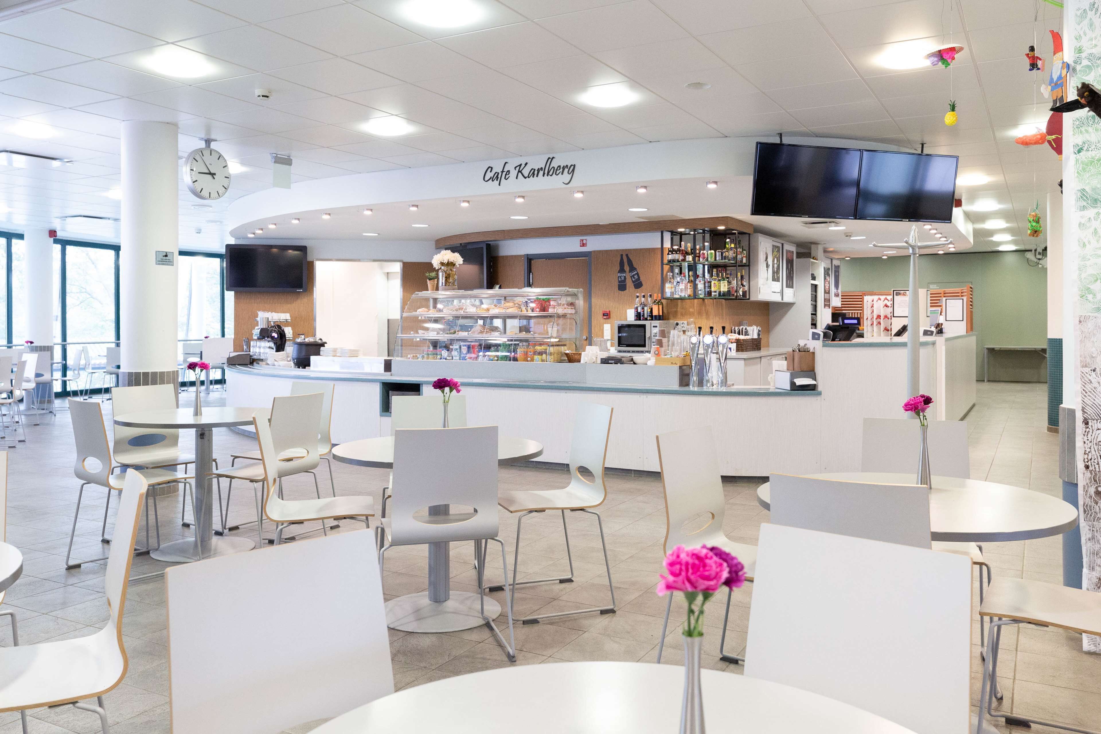 A modern cafe with a counter, seating area, and a TV mounted on the wall.