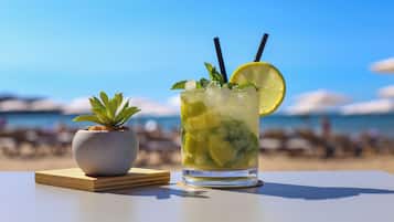 Un vaso transparente con hielo, hojas de menta y una rodaja de limón sobre una mesa con una pequeña planta en maceta al lado.