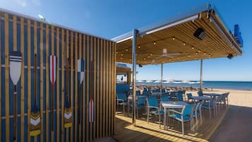 Un restaurante frente al mar con terraza al aire libre, una cubierta de madera y vistas al océano.