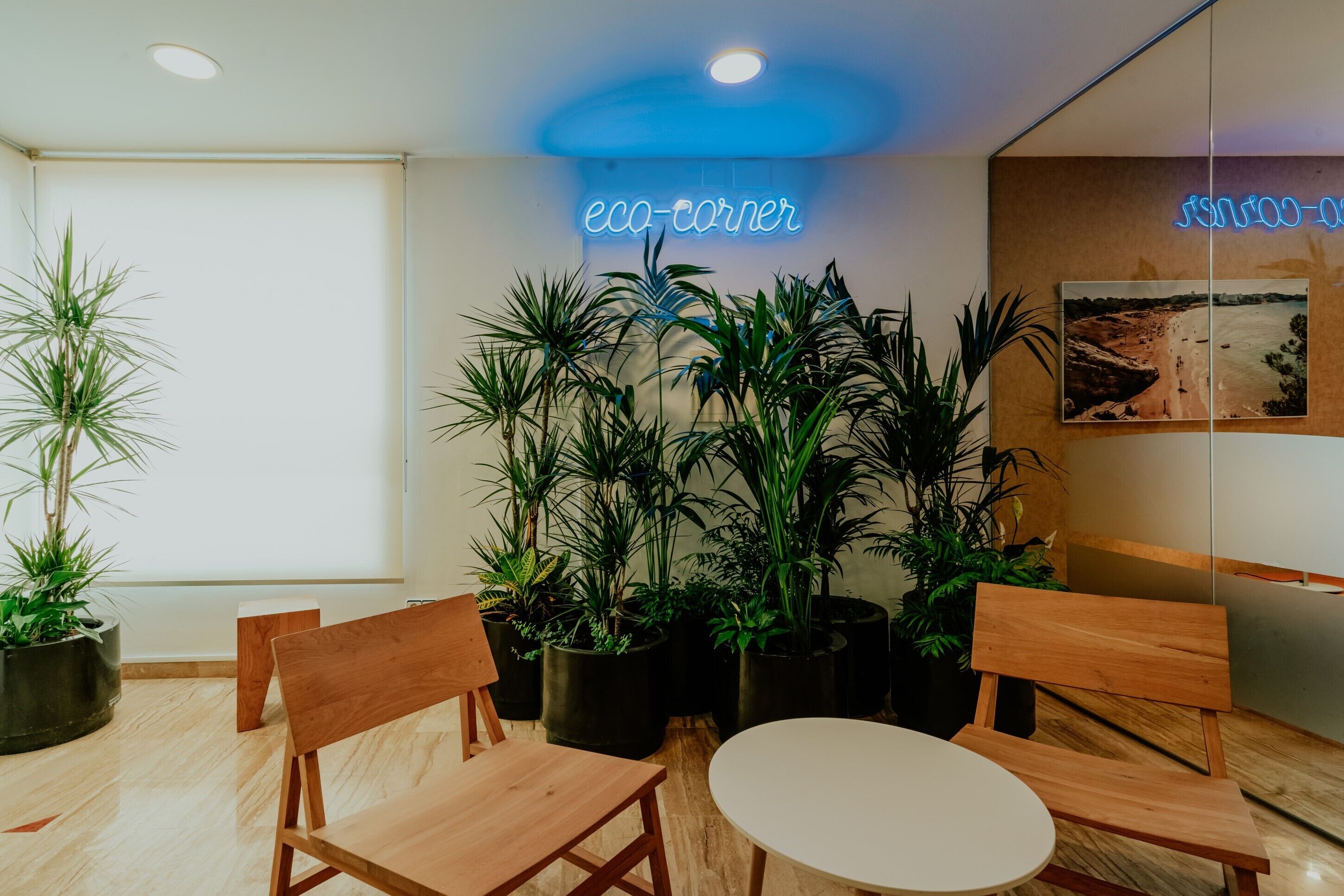 A modern indoor space with wooden furniture, potted plants, and a neon sign reading "eco-corner".