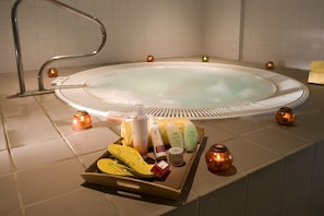 Ein Wellnessbereich mit Whirlpool, verschiedenen Pflegeprodukten und Kerzen.