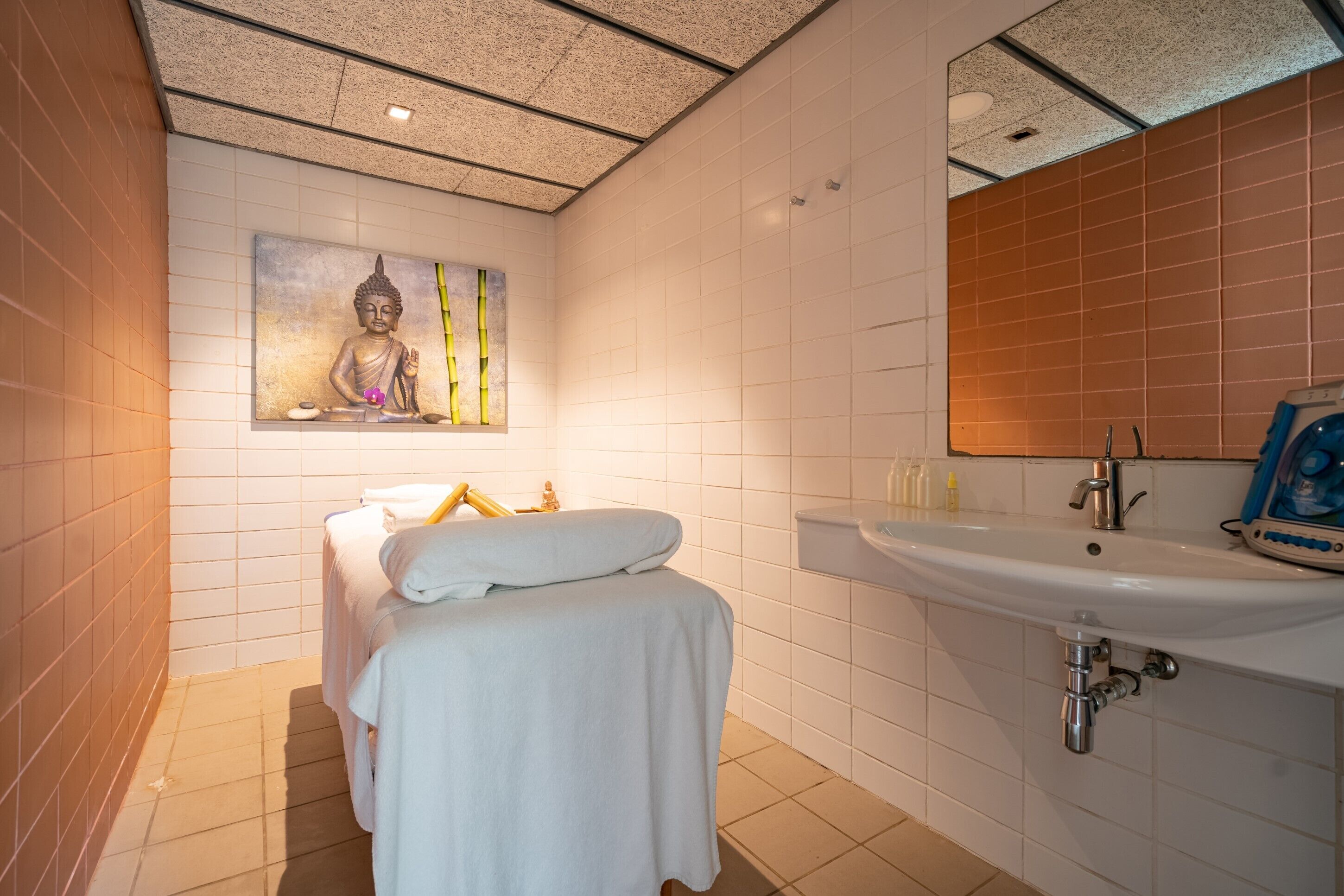 Ein Badezimmer mit Bett, Waschbecken und einer Buddha-Statue an der Wand.