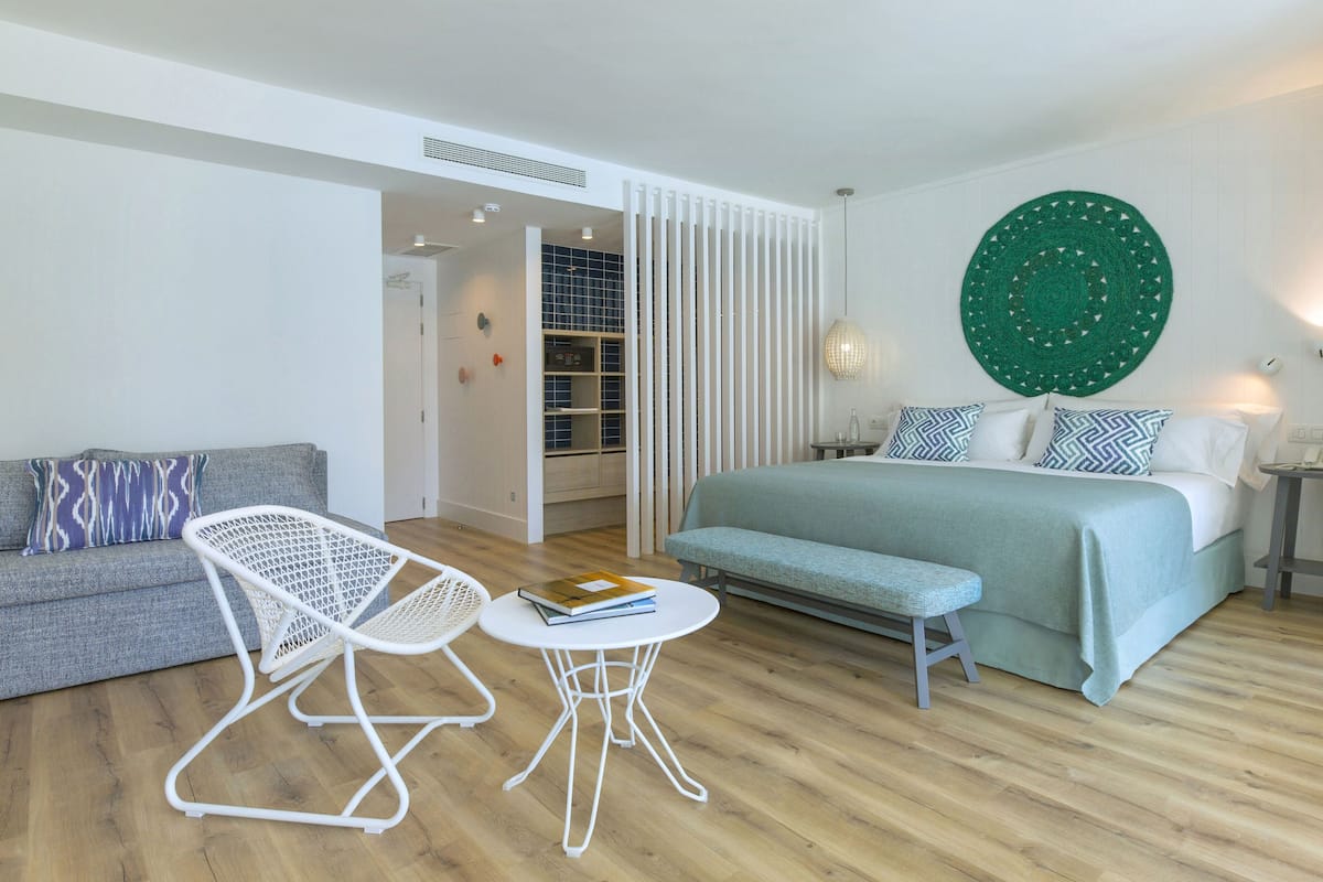 A modern bedroom with a bed, a sofa, a chair, and a small table.