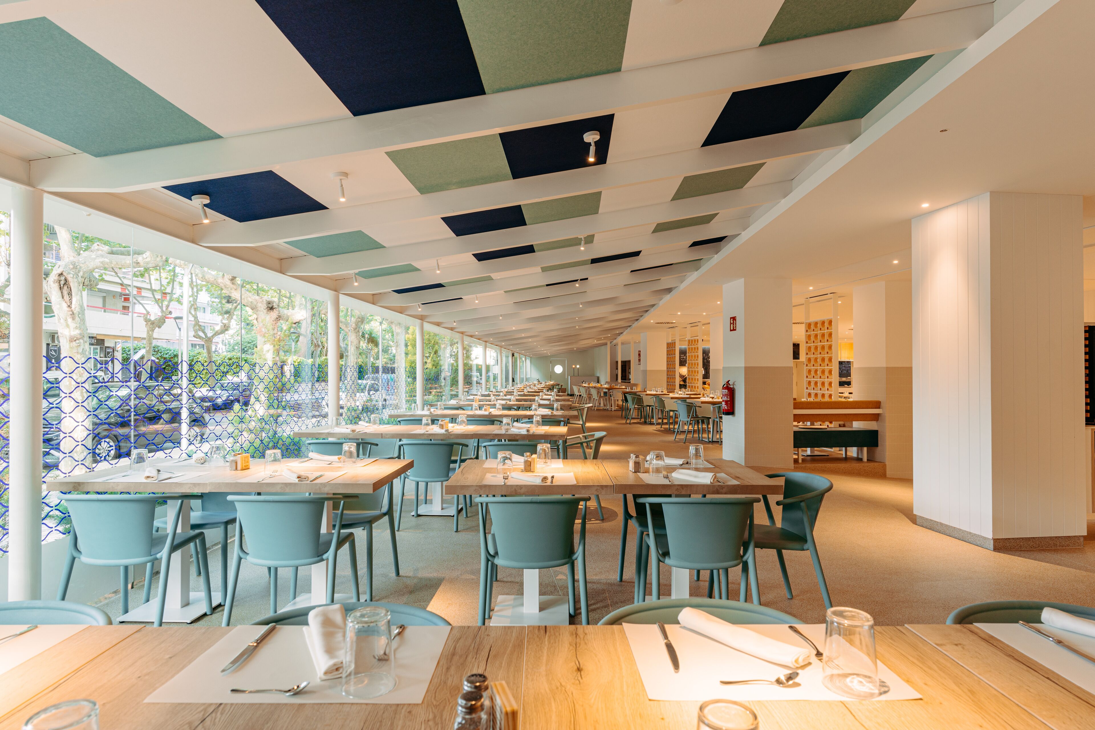 Un restaurante espacioso con techos altos, ventanas amplias y una decoración interior moderna.