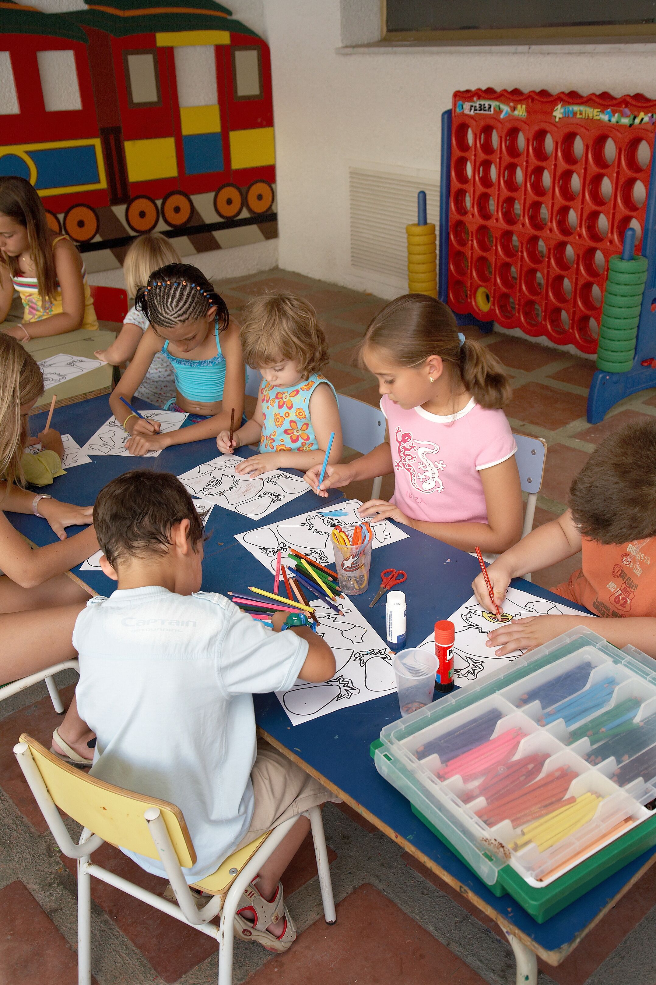A group of children engaged in a coloring activity at a table with art supplies.
