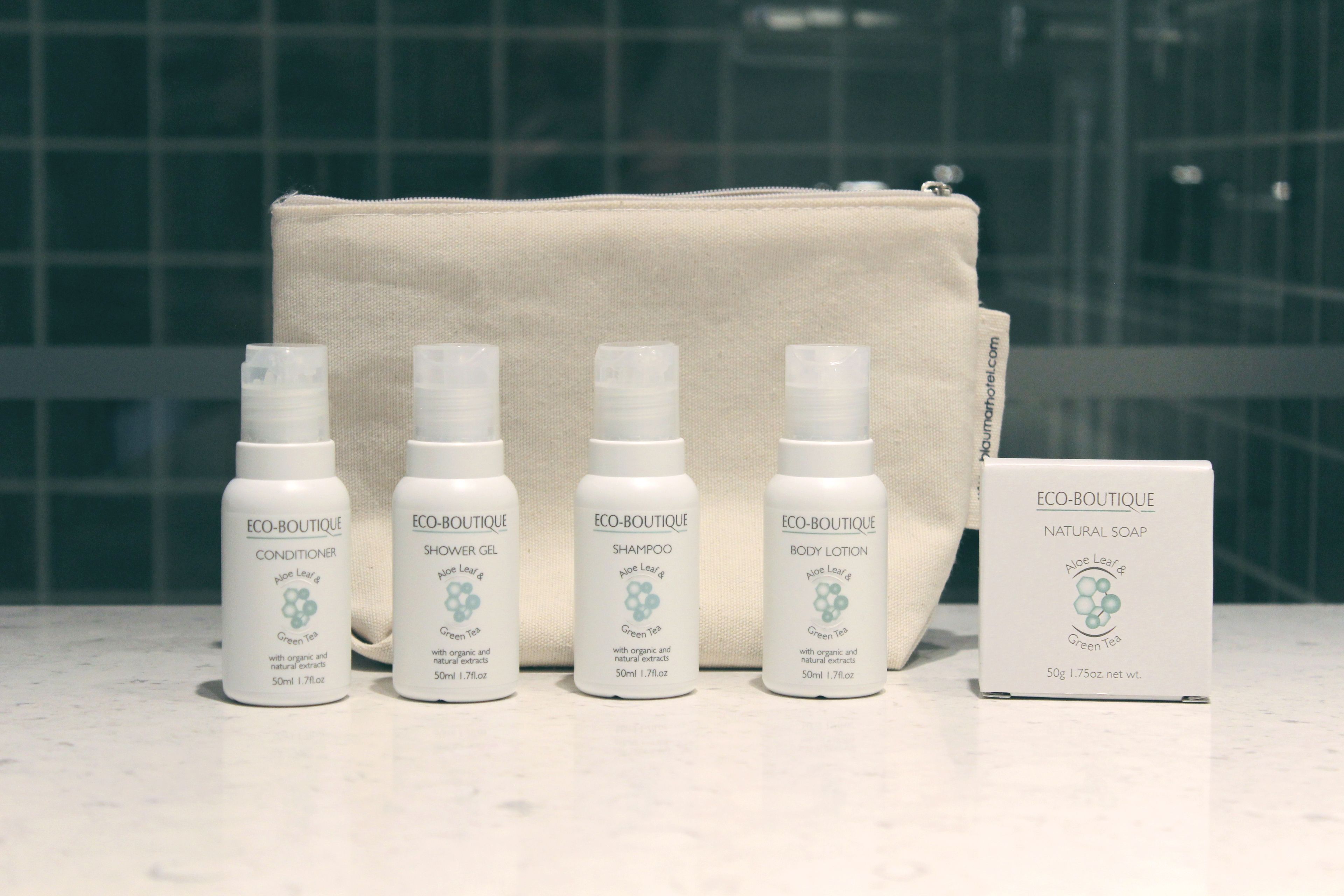 Cinco botellas de productos naturales Eco-Boutique y una caja de jabón natural sobre una superficie de mármol.
