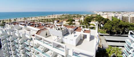 A high-rise hotel with multiple balconies, a rooftop pool, and a view of the beach and ocean.