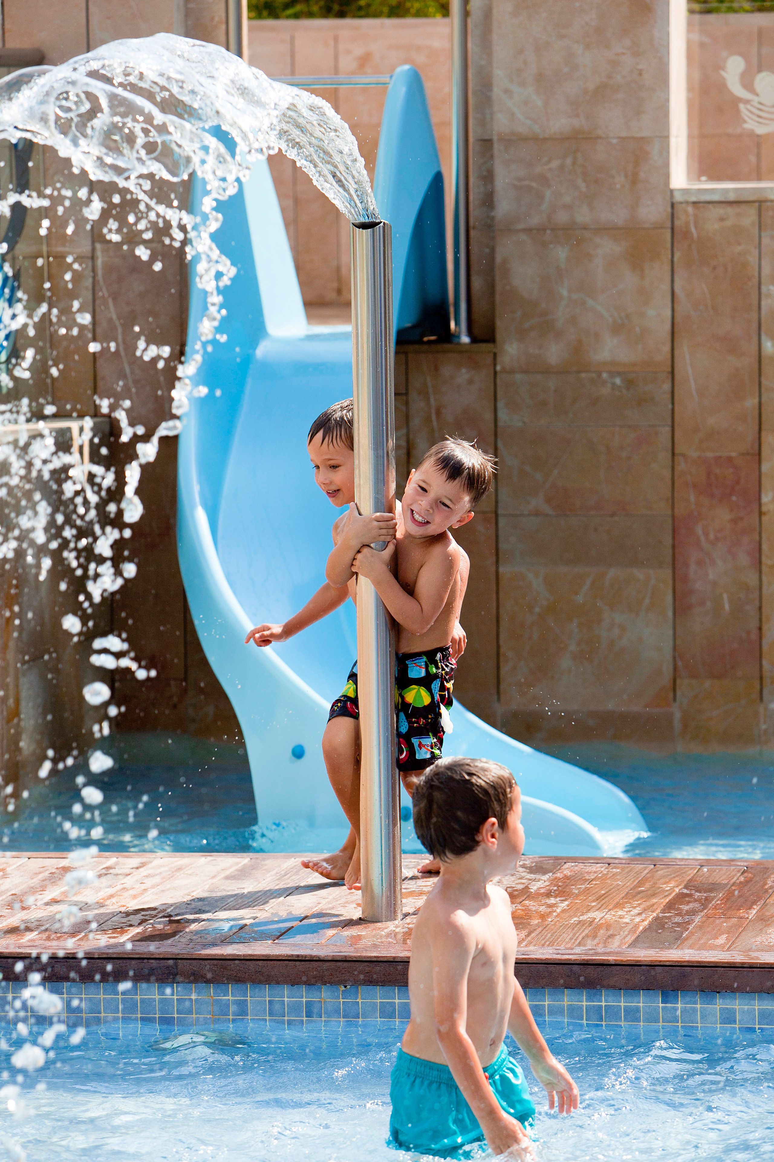 A water slide at a poolside area with a metal pole and a blue slide.