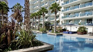 A modern hotel with a pool area, palm trees, and outdoor seating. - Blaumar Hotel Salou (Salou)