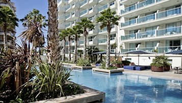 Una piscina al aire libre, sombrillas, sillones reclinables de piscina