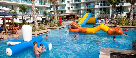 A hotel pool area with multiple levels, palm trees, and water slides.
