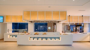 A modern kitchen with a central island, glass display cases, and a large window with yellow blinds. - Blaumar Hotel Salou (Salou)