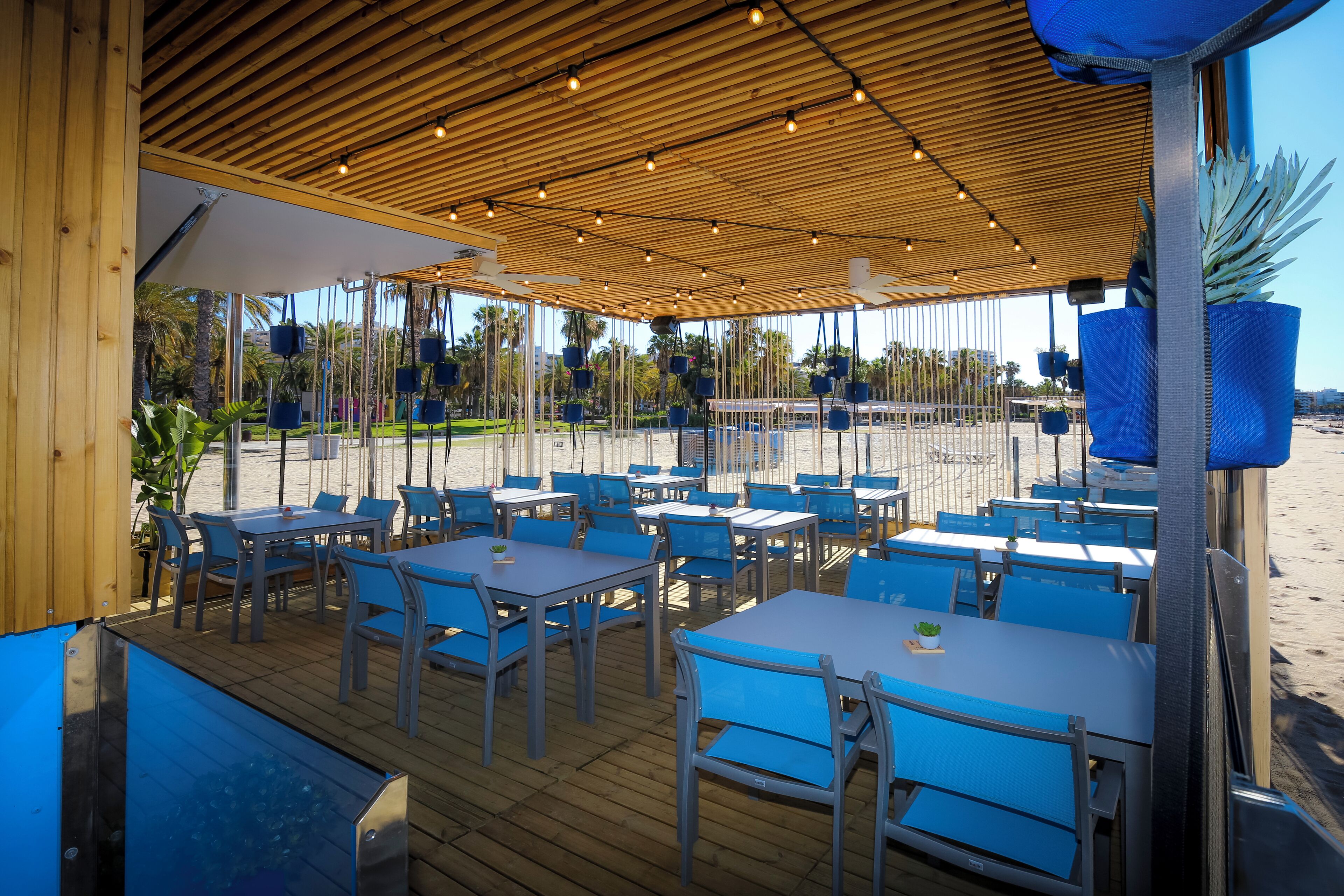 Un espace de restauration en plein air avec des tables et des chaises, un plafond en bois et une vue sur la plage.