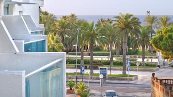 Un edificio moderno con fachada de vidrio, palmeras y vista al mar.